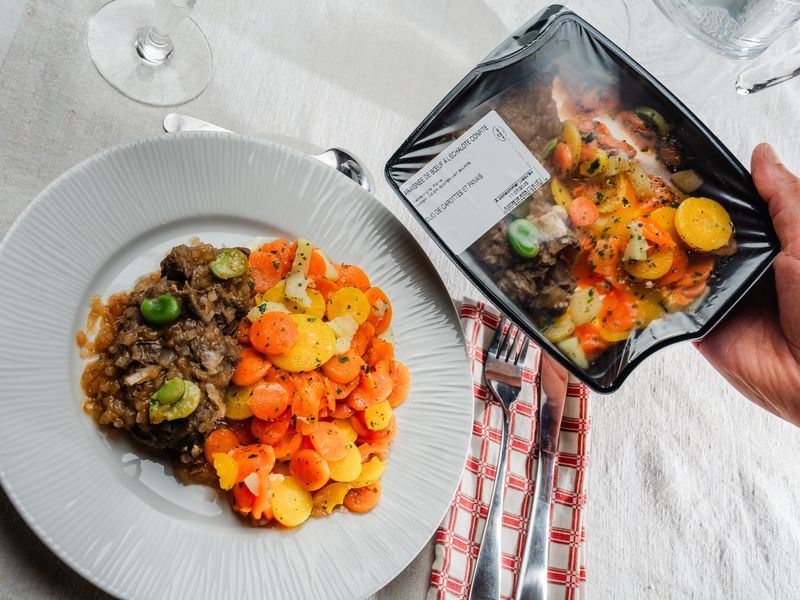 Une assiette et une barquette avec une araignée de bœuf à l'échalote confite et duo de carottes et panais