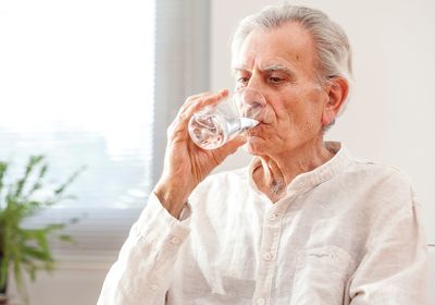 Un grand-père buvant un verre d'eau