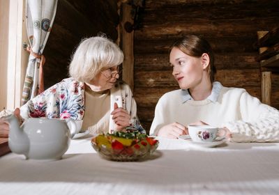 Une mamie discutant avec sa petite fille entrain de boire un thé