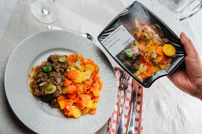 Une assiette et une barquette avec une araignée de bœuf à l'échalote confite et duo de carottes et panais