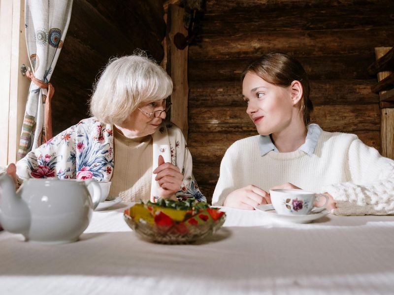 Une mamie discutant avec sa petite fille entrain de boire un thé